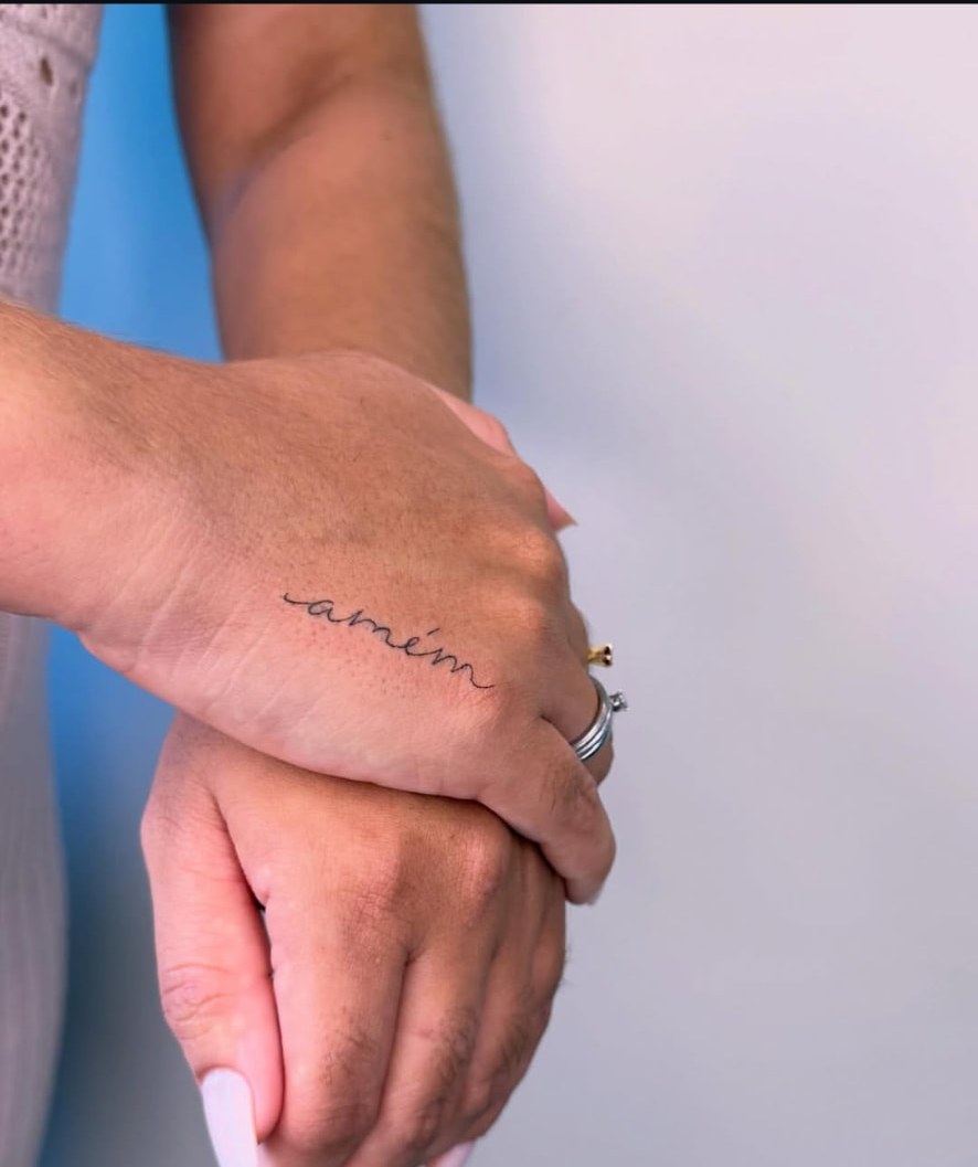 Tatuagem fine line com a escrita amém na mão