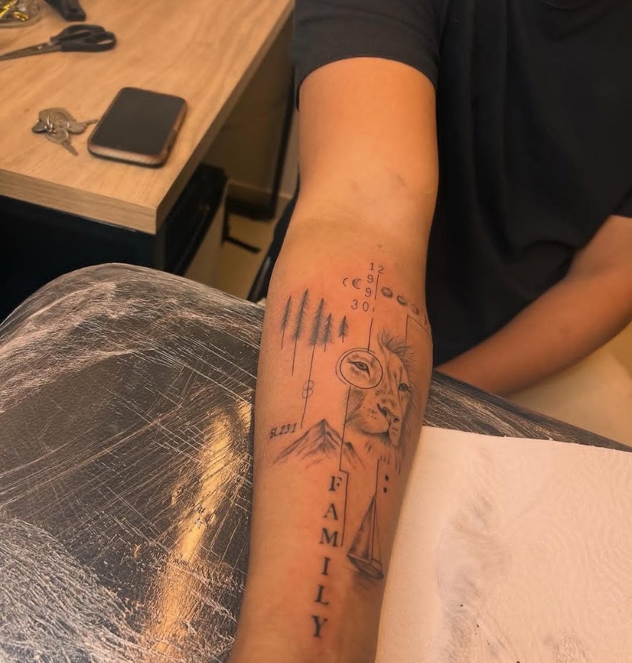 Tatuagem de braço com leão, montanhas e a palavra family